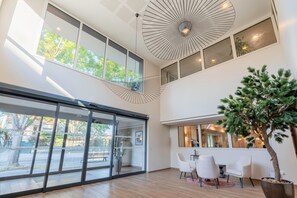 Een modern interieur met grote ramen, een plafondventilator en een kamerplant.