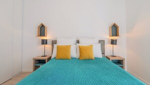 Ein Schlafzimmer mit einem Bett, zwei Nachttischen, zwei Lampen und einem Fenster.