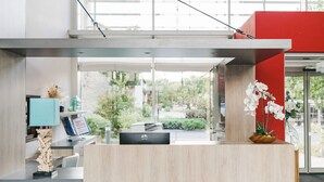 A modern reception desk with a computer, a blue lamp, and a decorative plant. - Quality Aparthotel Dinan (Dinan)