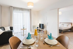 A hotel room with a dining area, a bed, a TV, and a bathroom. - Quality Aparthotel Dinan (Dinan)