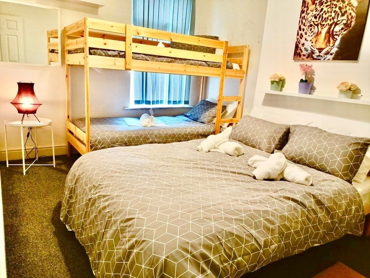 Une chambre avec deux lits superposés, un bureau avec une lampe et un tableau au mur.