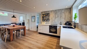 A modern kitchen with wooden flooring, a dining area with a wooden table and chairs, and built-in appliances. - Beautiful home in Hjørring with WiFi (Hjørring)