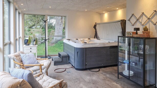 A modern bedroom with a large window, a hot tub, a glass cabinet, and a wicker chair. - Beautiful home in Hjørring with WiFi (Hjørring)
