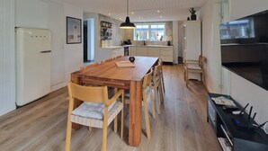 A modern kitchen with a wooden dining table, chairs, a hanging light fixture, and a built-in oven. - Beautiful home in Hjørring with WiFi (Hjørring)