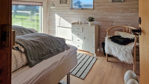 A bedroom with a bed, a dresser, a chair, and a TV on the wall. - 3 bedroom beautiful home in Løkken (Løkken)