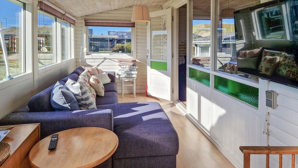 A cozy living area with a sofa, a small round table, and a television mounted on a wall. - 3 bedroom beautiful home in Løkken (Løkken)