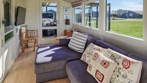 A cozy living room with a sectional sofa, a television, and large windows offering a view of the outdoors. - 3 bedroom beautiful home in Løkken (Løkken)