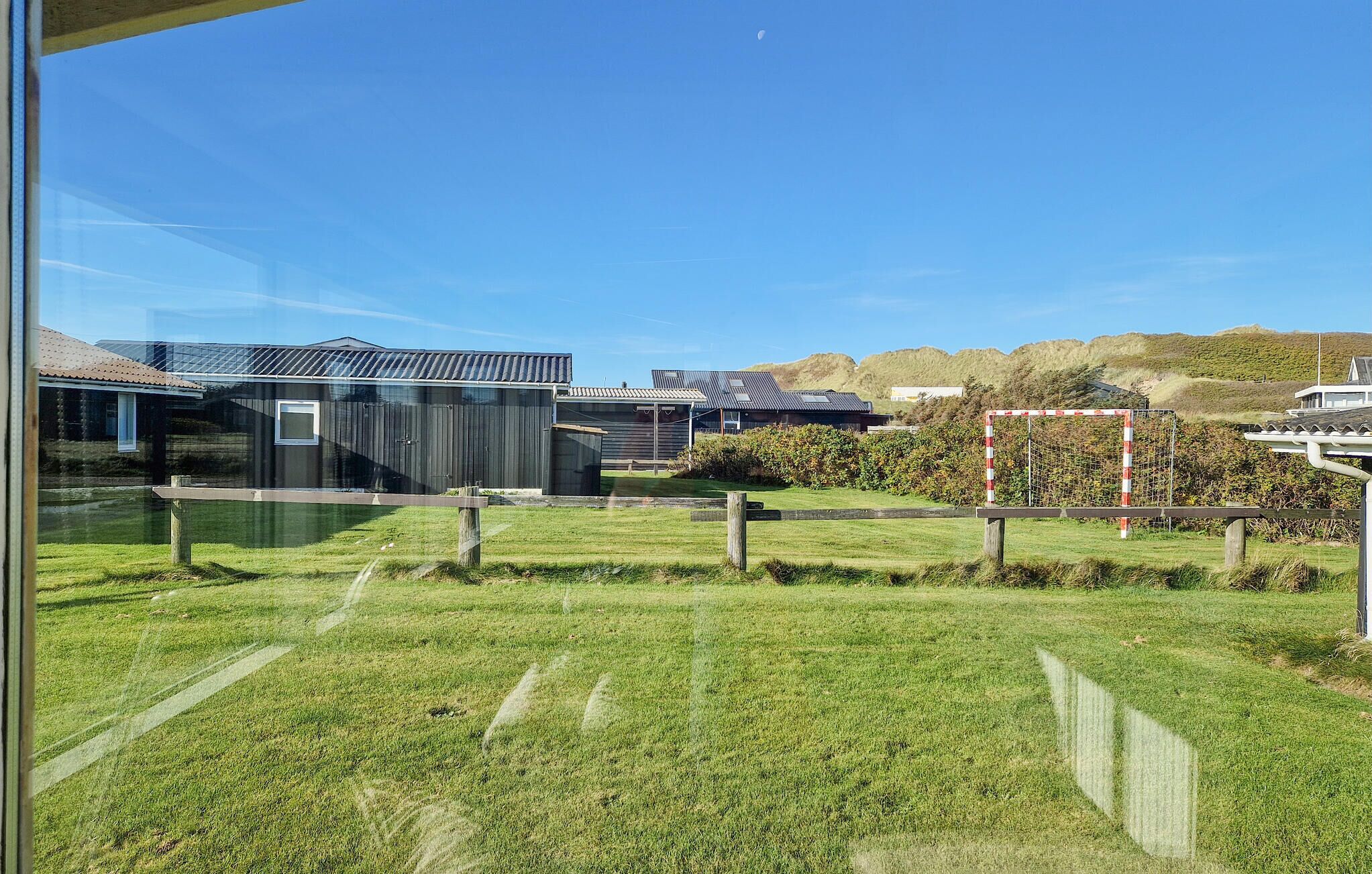 Un ensemble immobilier moderne composé de plusieurs bâtiments, avec un terrain herbeux et une colline en arrière-plan.