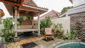 A covered outdoor seating area with a pool, stone flooring, and tropical plants. - Charming 8-bedroom guesthouse with shared kitchen, only 1 km from the beach. (Banjar)