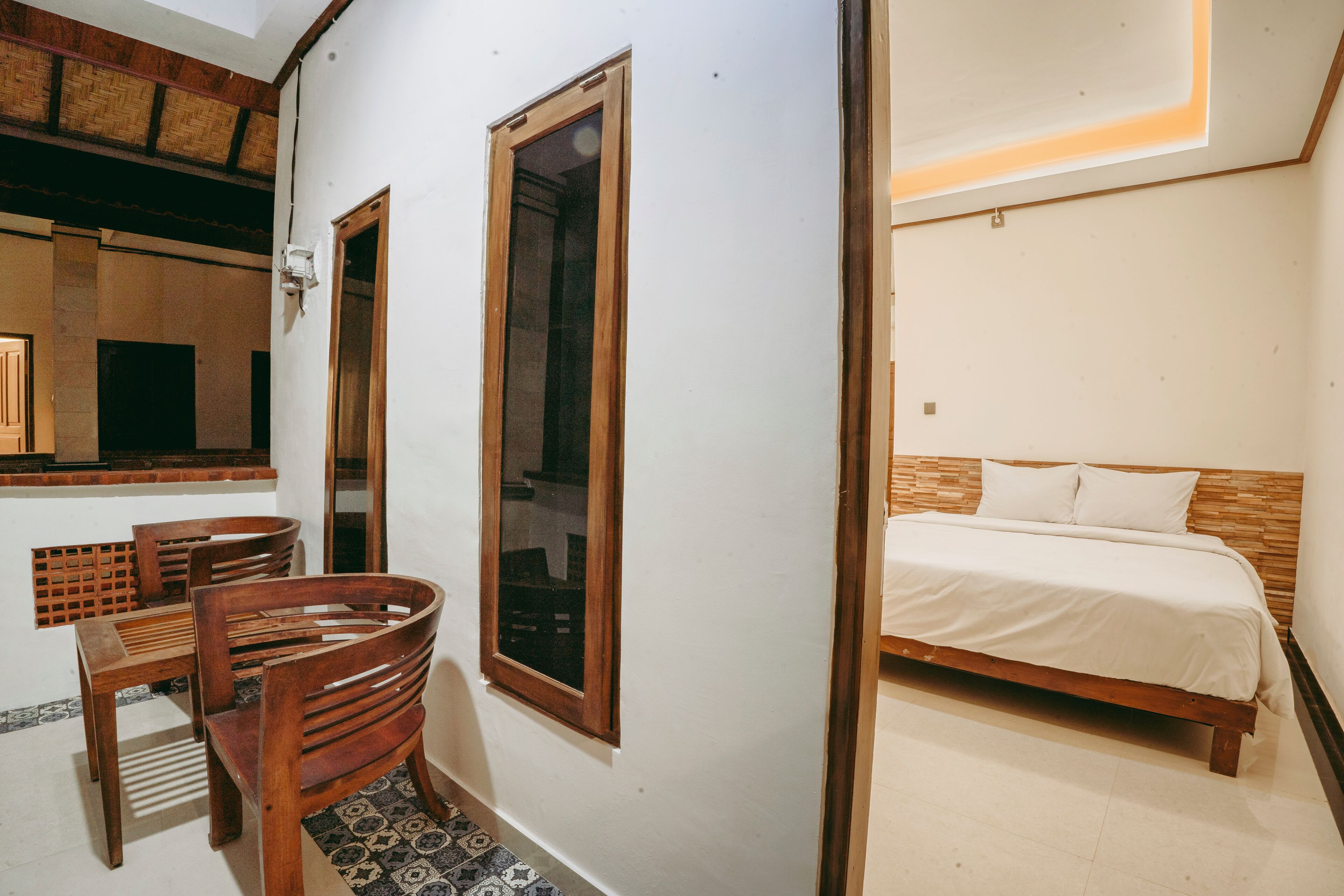 Een slaapkamer met een houten bed, een tafeltje en twee stoelen.