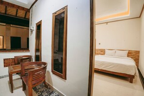 Un dormitorio con una cama de madera, una mesita pequeña y dos sillas.