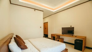 A bedroom with a bed, wooden headboard, a desk with a television, and a small cabinet. - Charming 8-bedroom guesthouse with shared kitchen, only 1 km from the beach. (Banjar)