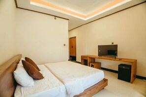 A bedroom with a bed, wooden headboard, a desk with a television, and a small cabinet. - Charming 8-bedroom guesthouse with shared kitchen, only 1 km from the beach. (Banjar)