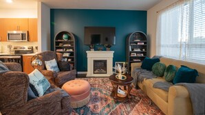 Ein Wohnzimmer mit Kamin, einem Fernseher darüber und zwei Bücherregalen.