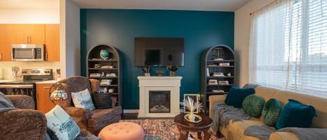 A living room with a fireplace, a television above it, and two bookshelves.