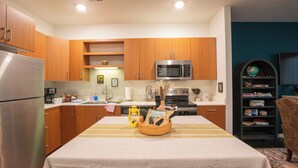 Eine moderne Küche mit Holzausbau, einem Edelstahlkühlschrank, einer Mikrowelle und einem Esstisch mit Streifenmuster.