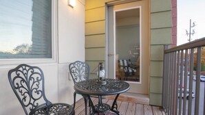Eine Holzterrasse mit zwei verzierten Metallstühlen und einem runden Tisch.