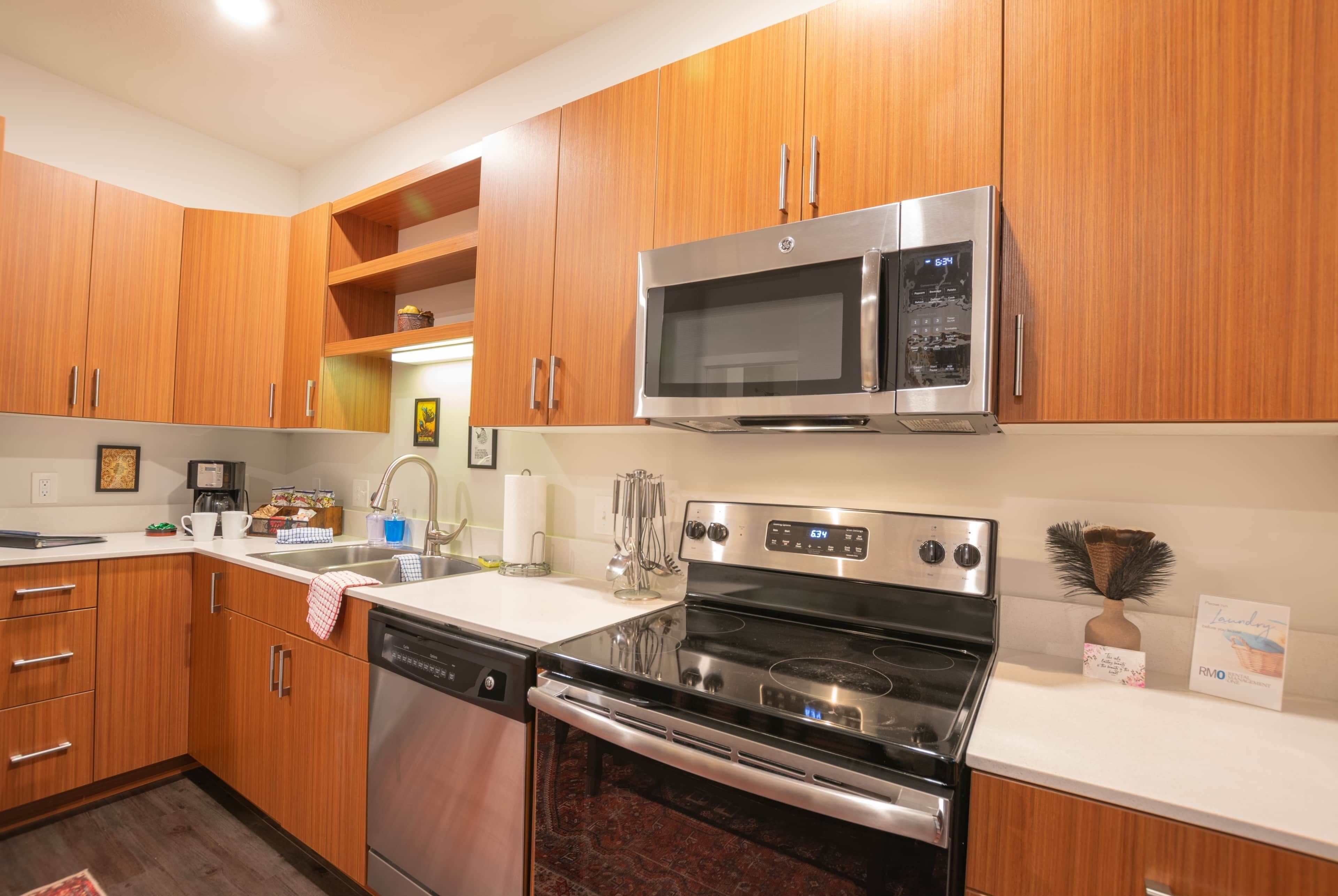 A modern kitchen with wooden cabinets, stainless steel appliances, a dishwasher, and a stove.