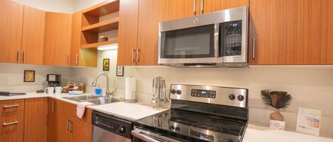 A modern kitchen with wooden cabinets, stainless steel appliances, a dishwasher, and a stove.