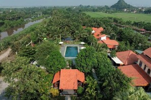 Un resort con varias construcciones, una piscina y exuberante vegetación.