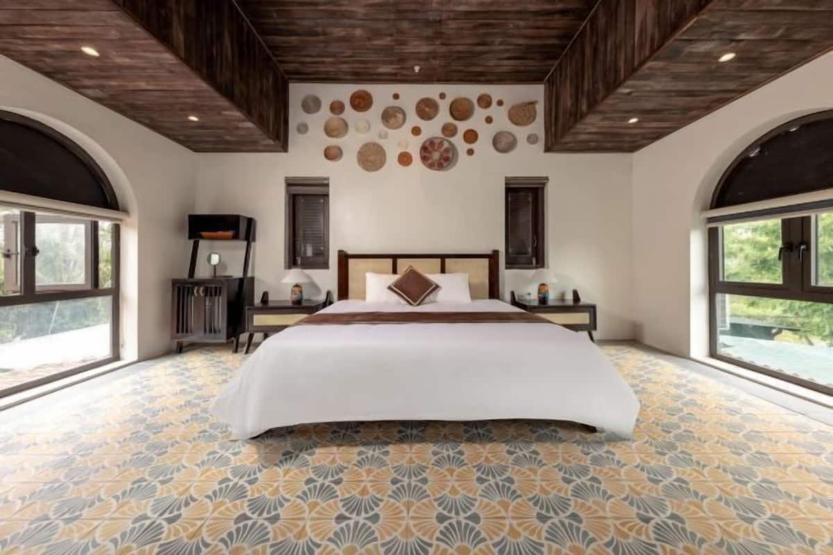 A large bed with a wooden headboard, a patterned floor, and a wall with circular decorations.