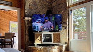 Una sala de estar con chimenea de piedra, televisor de pantalla plana y un ventanal grande.