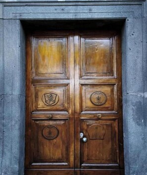 A wooden double door with a metal handle and a circular emblem on the lower right panel. - Hotel Villa Nunziante  (Scafati)