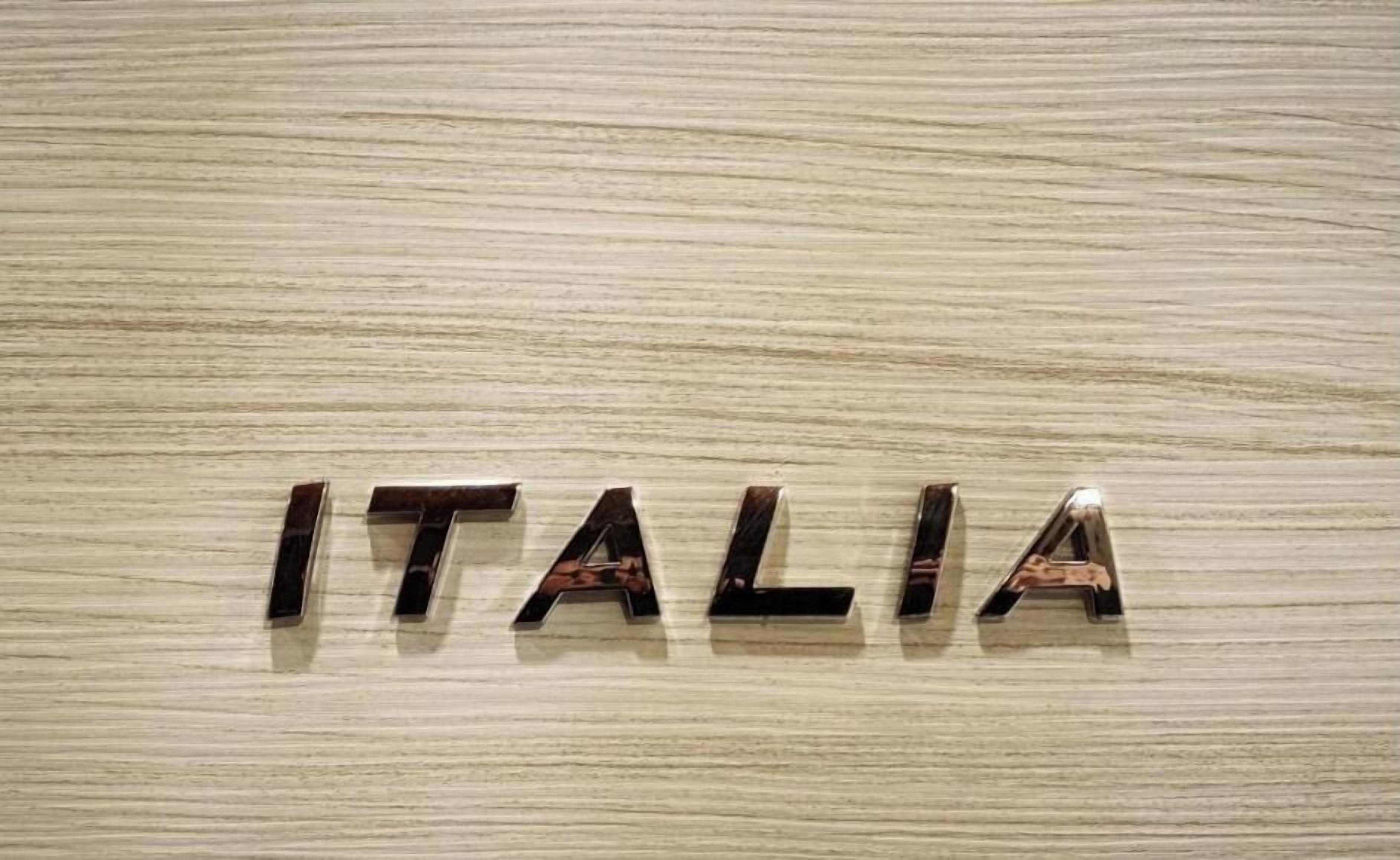 La palabra 'ITALIA' escrita en letras metálicas sobre una superficie de madera.