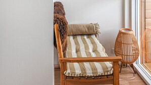 A wooden chair with a striped cushion, a woven chair, and a fur throw on a balcony. - Nice home in Hanstholm with house sea view (Hanstholm)