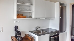 A compact kitchen with white cabinets, a built-in sink, a coffee maker, and an oven. - Nice home in Hanstholm with house sea view (Hanstholm)