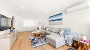 Una sala de estar moderna con sofá, mesa de centro y televisor.