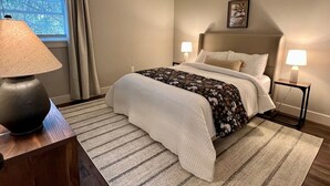 A neatly arranged bedroom with a bed, bedside lamps, a window with curtains, and a picture on the wall. - Peaceful Home near Historic Strasburg (Lancaster)