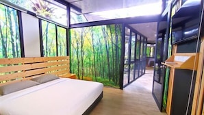 Une chambre moderne avec un grand lit, une tête de lit en bois et une fresque représentant une forêt sur le mur.