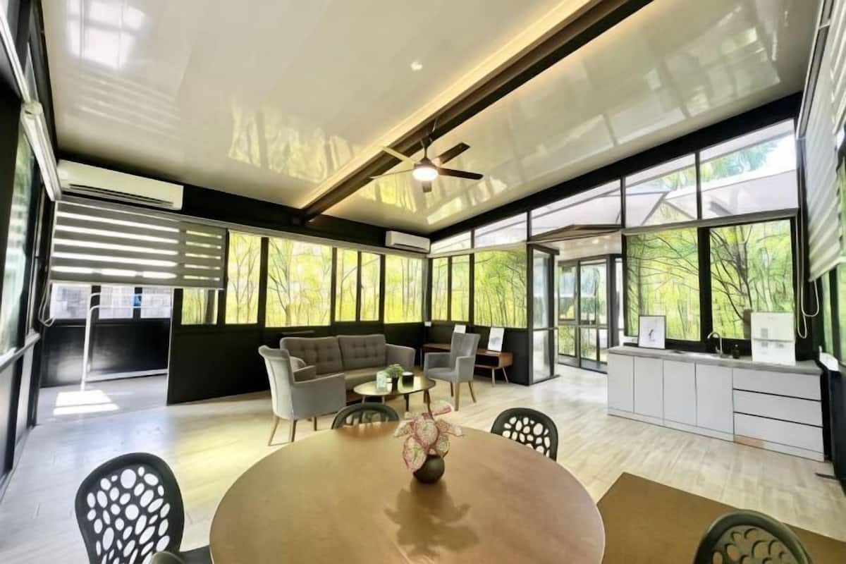 Un interior moderno con zona de comedor, sofás y ventanas amplias.