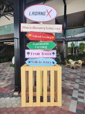 A sign with multiple directional arrows and text indicating various attractions such as 'Animal Feeding,' 'Sustainable Farming,' 'Fruit Trees,' and 'Walk-in Wardrobe.' - XChalet X Park Iskandar Puteri (Iskandar Puteri)