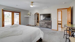 Ein Schlafzimmer mit einem großen Bett, einem Fernseher, einem Schreibtisch mit Stuhl und einem Balkon.
