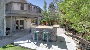 Ein Haus mit überdachter Terrasse, Sitzgelegenheiten im Freien und Grillplatz.