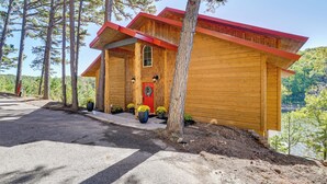A wooden cabin with a red roof, surrounded by trees and a clear sky. - Grand Lake Waterfront Getaway w/ Boat Slip! (Eucha)