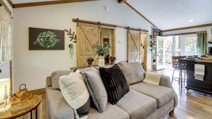 A cozy living room with a sofa, decorative pillows, a wooden-framed ceiling, and a view to the outside. - Raft, Hike & Fish: Quiet Couple's Escape in Murphy (Murphy)