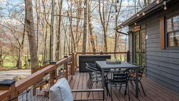 Une terrasse en bois avec une table et des chaises, entourée d’arbres.