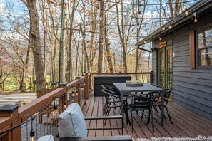 A wooden deck with a table and chairs, surrounded by trees. - Family Getaway to Bear Paw! Theatre, Firepit, Hot tub! (Sevierville)