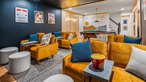 En hyggelig lounge med gule sofaer, et billardbord og et plakat af 'Sevierville'.