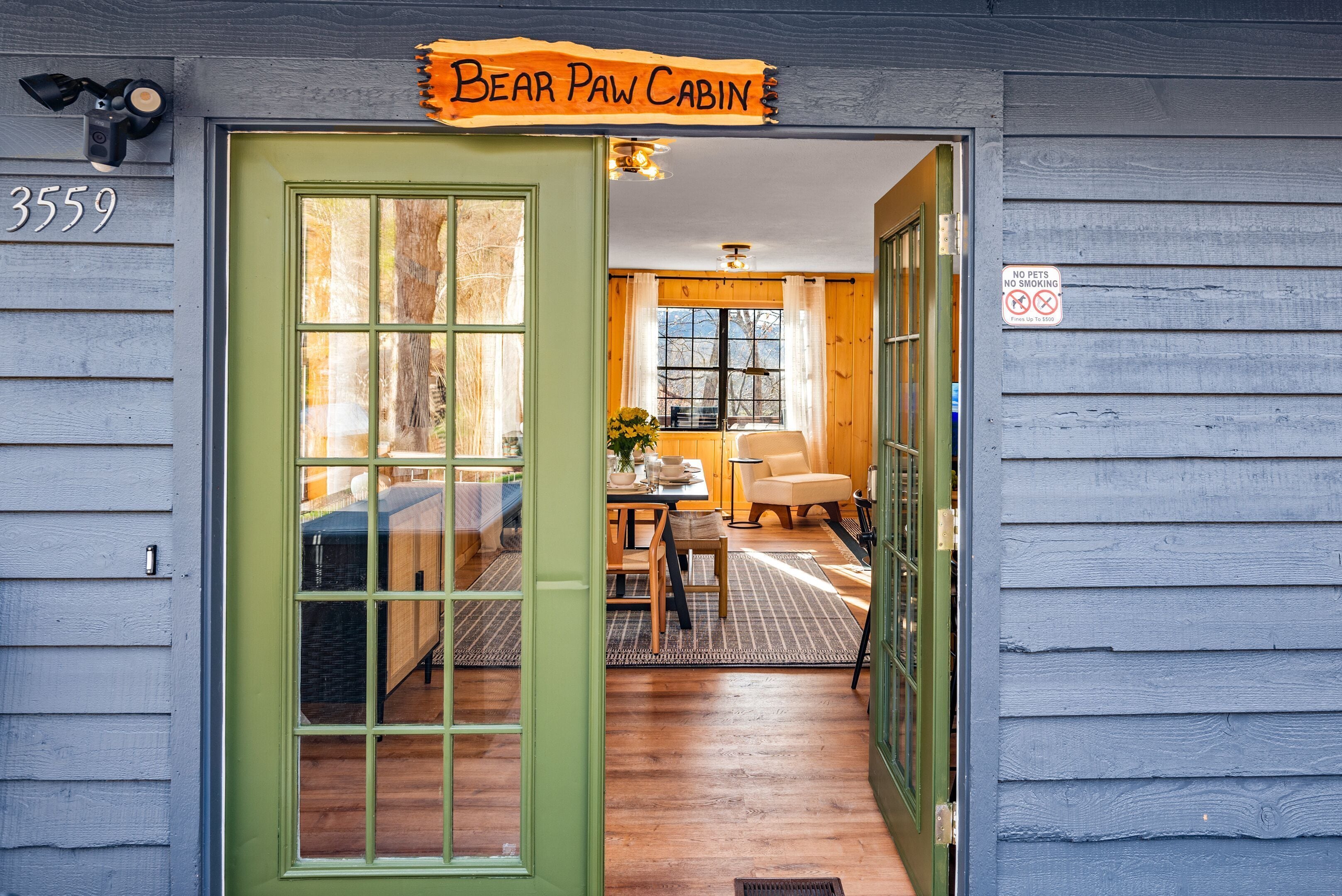 L’entrée du chalet se distingue par une porte verte, une enseigne indiquant « Bear Paw Cabin » et un panneau « Animaux et tabagisme interdits ».
