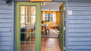 En hytte med en grøn dør, et skilt der siger "Bear Paw Cabin", og et skilt med teksten "Ingen kæledyr, ingen røg“.