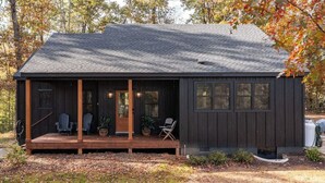Une cabane avec une véranda, deux chaises et une petite table.