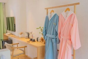 A room with a wooden desk, a chair, two robes hanging on a rack, a plant, and a coffee maker. - Anju·Rizhao Jinshan Designers' Panoramic Rooftop Cafe and Snow Mountain View (Lijiang)