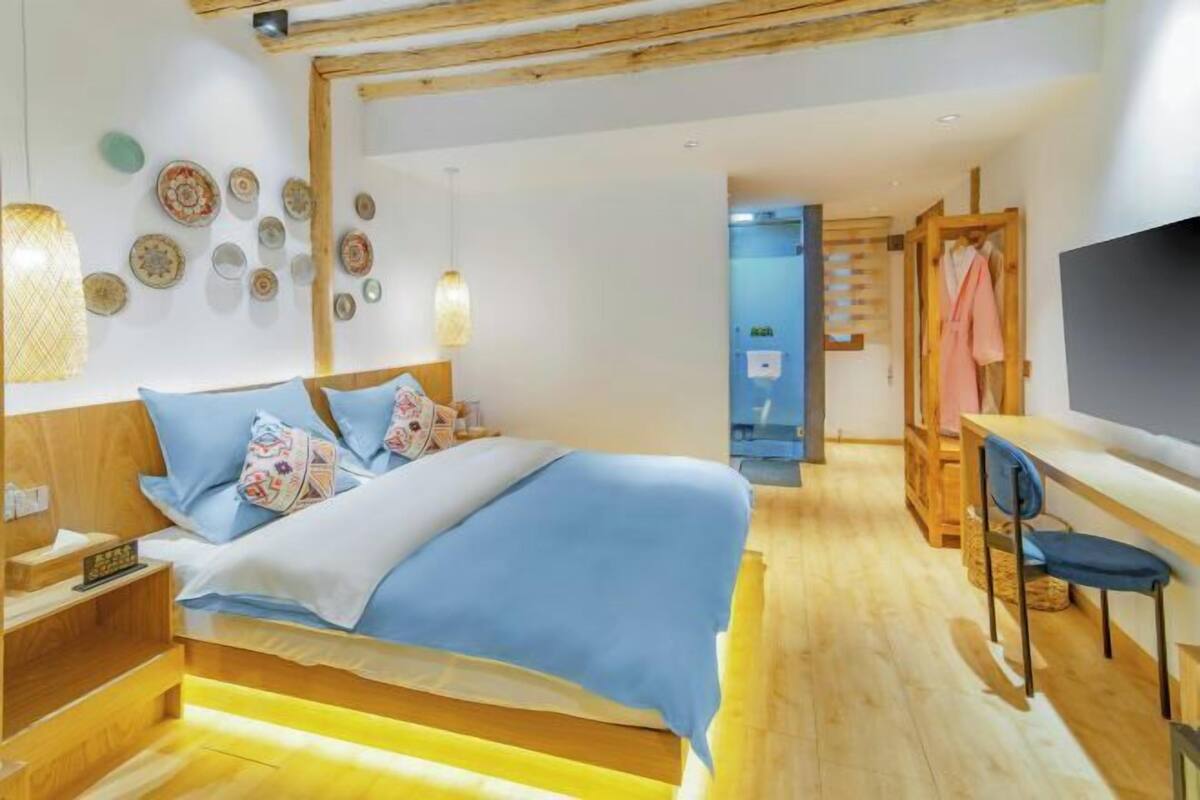 A bedroom with a bed, bedside tables, a desk, and a TV.