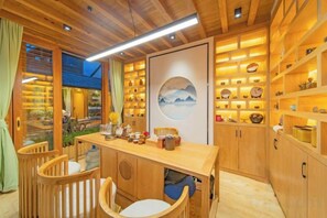 A wooden interior with a dining area, shelves with decorative items, and a view through a window. - Anju·Rizhao Jinshan Designers' Panoramic Rooftop Cafe and Snow Mountain View (Lijiang)