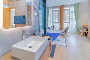 A modern bathroom with a large white bathtub, a blue freestanding bathtub, a mirror, and a sink. - Anju·Rizhao Jinshan Designers' Panoramic Rooftop Cafe and Snow Mountain View (Lijiang)