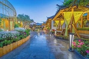 A pathway lined with traditional wooden structures and potted plants, leading to a central building with a curved roof. - Anju·Rizhao Jinshan Designers' Panoramic Rooftop Cafe and Snow Mountain View (Lijiang)